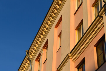 The yellow facade of the building in the evening sun. The walls of a house in the city in summer. Government buildings.