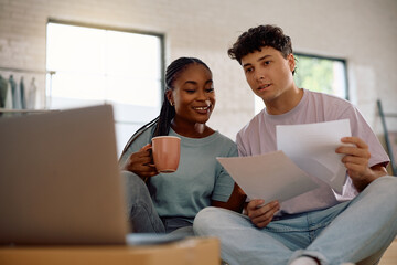 Young couple of new homeowners using laptop while doing their taxes.