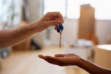Close up of black woman receiving key of her new apartment from real estate agent.