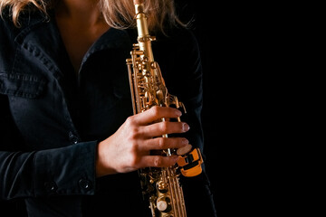soprano saxophone in the hands of a girl on a black background