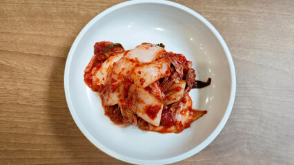 Close-up of Traditional Korean Kimchi in a White Ceramic Bowl on Wooden Table