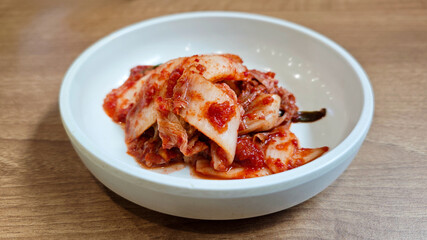 Close-up of Traditional Korean Kimchi in a White Ceramic Bowl on Wooden Table
