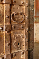 Fragment of an antique metal door with lock and round handle. Part of an old vintage iron door.