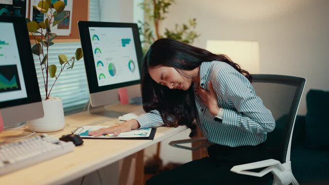Asian accountant working late at her desk suddenly experiences chest pain and shortness of breath, highlighting the risks of stress and overwork in a demanding office environment