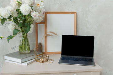 Laptop with blank screen, empty frames, flowers in vase, books and female accessories on dresser...