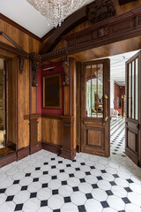 the chic expensive interior of the living room in the historical Baroque style, tiles on the floor, walls decorated with wood. the furniture is in a historical style.