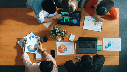 Top down view of business woman explain and present financial chart. Diverse group discuss and listen presentation about stock market statistic at meeting table with investment graph. Convocation.