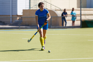 Young female player leading the ball in a field hockey match
