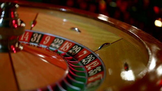The casino is decorated in warm red tones, the roulette wheel is absorbed in the moment of the game.