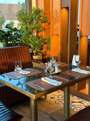 Cozy restaurant interior with elegantly set table, ready for guests. the warmth of the wooden accents and green plants create a welcoming atmosphere.