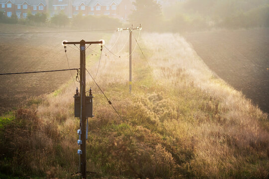Utility pole and power lines in a lush green countryside in england uk