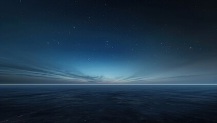 Dark blue sky with a few stars and a large body of water. The water is calm and the sky is clear