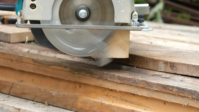 Working circular saw cutting a piece of a wooden timber.