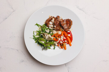 A hearty lunch with meat and vegetables on a large white plate.