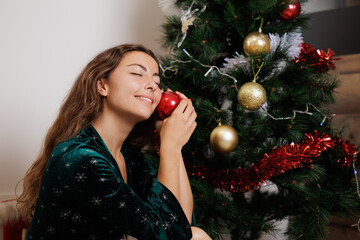 Young woman in Christmas dress decorating her house and putting up the Christmas tree. Christmas is a time of sharing with loved ones. Wishes, prosperity, new year. Shared happiness.