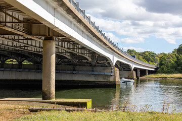 Motorway bridge in the UK with a passing boat, Image shows a bridge supporting the M27 over a river as traffic passes by on top as a small boat passes by underneath on a cold Autumn day
