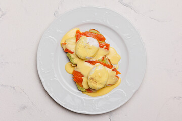 A hearty brunch of toast, avocado, salmon and poached eggs with cheese sauce.