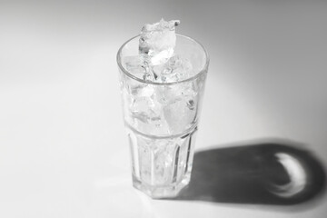 One glass with ice for refreshing drink on grey background, closeup