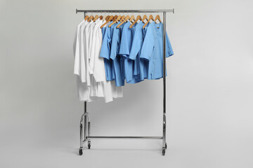 Different medical workers' uniforms on clothing rack against white background