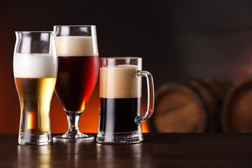 Glasses with different types of beer on wooden table in bar. Space for text