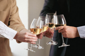 People clinking glasses of wine indoors, closeup
