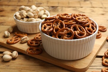 Delicious pretzel crackers and pistachios on wooden table, closeup