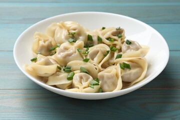 Delicious pelmeni with green onion on blue wooden table, closeup