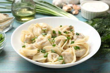 Delicious pelmeni with green onion served on blue wooden table, closeup