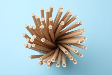 Bamboo drinking straws on light blue background, top view