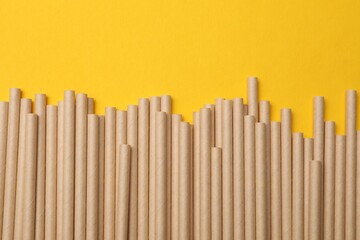 Bamboo drinking straws on yellow background, top view. Space for text