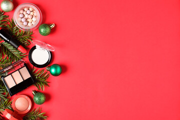 Flat lay composition with makeup products and Christmas decor on red background, space for text