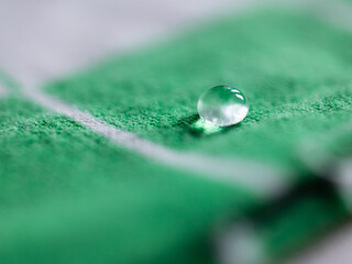 Single drop of water laid down on a green cloth
