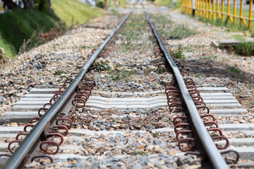 Fototapeta premium Macro photo of a train tracks or railway in sunny day with stones and grass