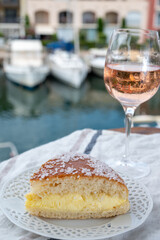 Wine and cakes of French Riviera, glasses of cold rose Cote de Provence wine and Tarte Tropezienne cake in yacht harbour of Port Grimaud, summer vacation in Provence, France