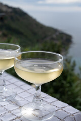 Cold sparkling wine, cava or champagne in two coupe glasses on table with sea water view