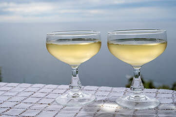 Cold sparkling wine, cava or champagne in two coupe glasses on table with sea water view