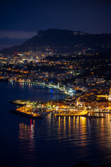Night view on French Riviera, lights of Menton old city and marina on blue Mediterranean Sea near French-Italian border, Monaco, Monte-Carlo, travel destination, panoramic view