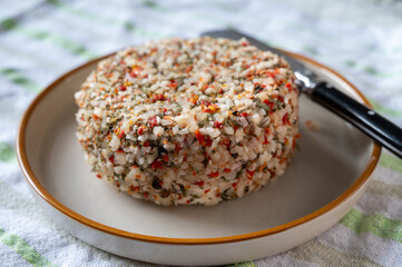 French cheese collection, fresh white soft goat cheese with aromatic herbs, garlic, parsley and red peppers close up