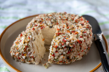 French cheese collection, fresh white soft goat cheese with aromatic herbs, garlic, parsley and red peppers close up