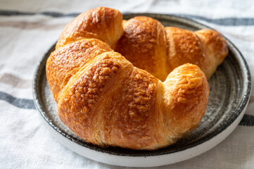 Fresh baked two buttered croissants served in restaurant for continental or French breakfast close up