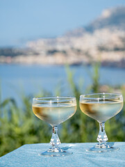 Sparkling wine, cava or champagne in two coupe glasses on table with view on Menton and Monte-Carlo, French Riviera, France is summer