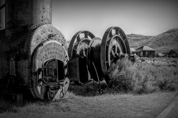Rustic mining equipment at Bodie State Historical Park, California. Vintage machinery including a boiler from Prescott Scott & Co, San Francisco, set against a backdrop of desert landscape.