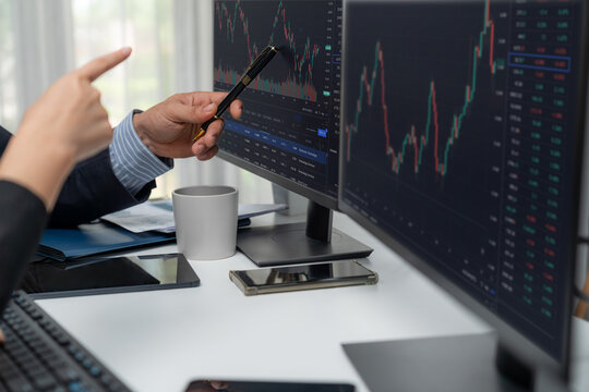 Focusing on hand pointing on pc screens with discussing dynamic stock market in two business traders real time currency rate investment on financial risk data base on desk at modern office. Postulate.
