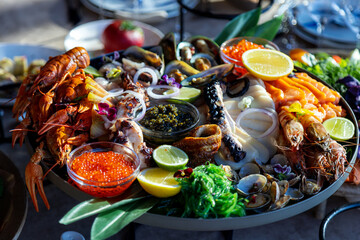 Closeup footage of assortment of seafood with sauces in a round tray, against blur background
