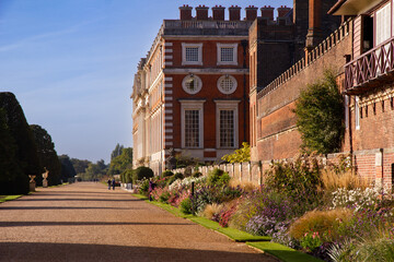 Georgian Facade of Hampton Court Palace and display of colourful flowers and plants in the surrounding borders