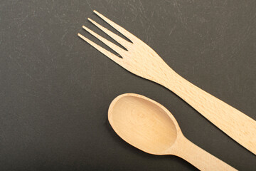 Wooden spoon and fork on black background