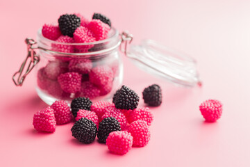 Sweet jelly candies in jar on pink background.