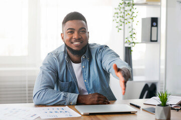 Partnership concept. Handsome African American Manager Extending hand for handshake after successful deal in office, copy space