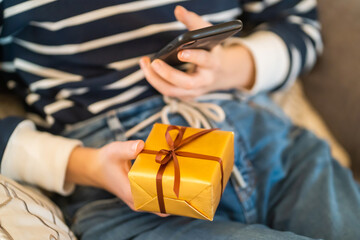GIrl holds a small nice packed gift in her hands.