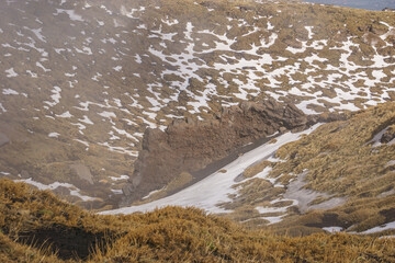 Bizarre rock formation at volcanic landscape of Mount Etna with black lava and yellow grass on a cloudy winter day, Catania, Sicily, Italy